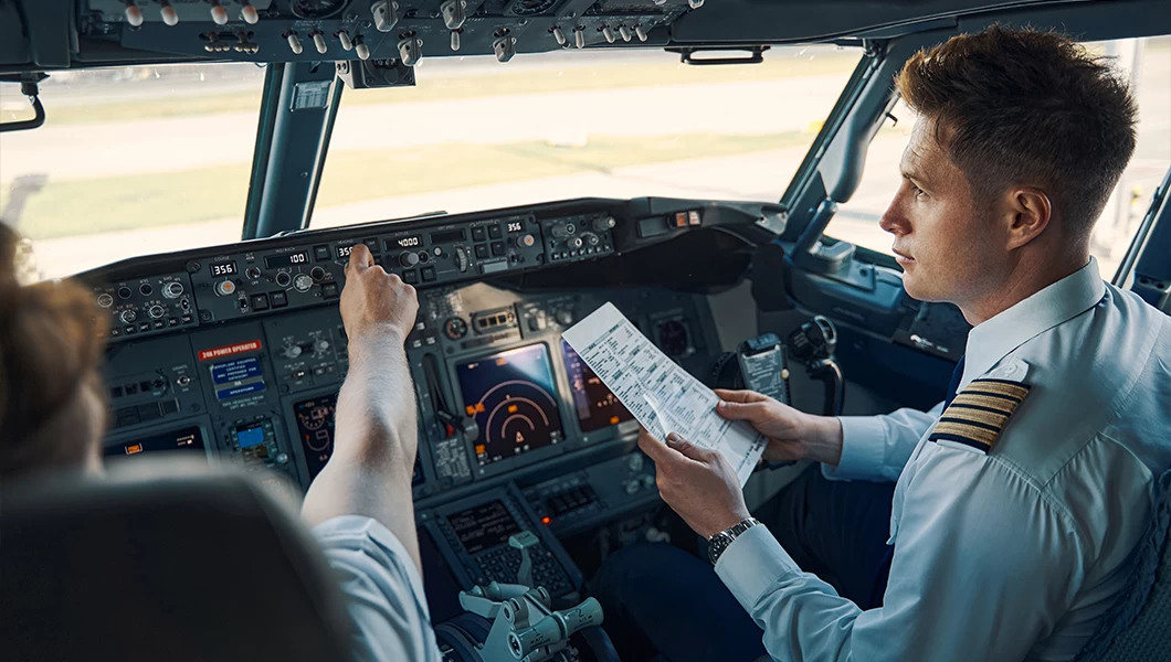 Pilots sitting in a cockpit, going through procedures.