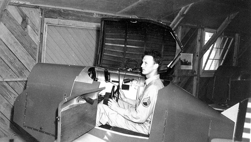 Link Trainer with a U.S. military pilot sitting inside the simulator.