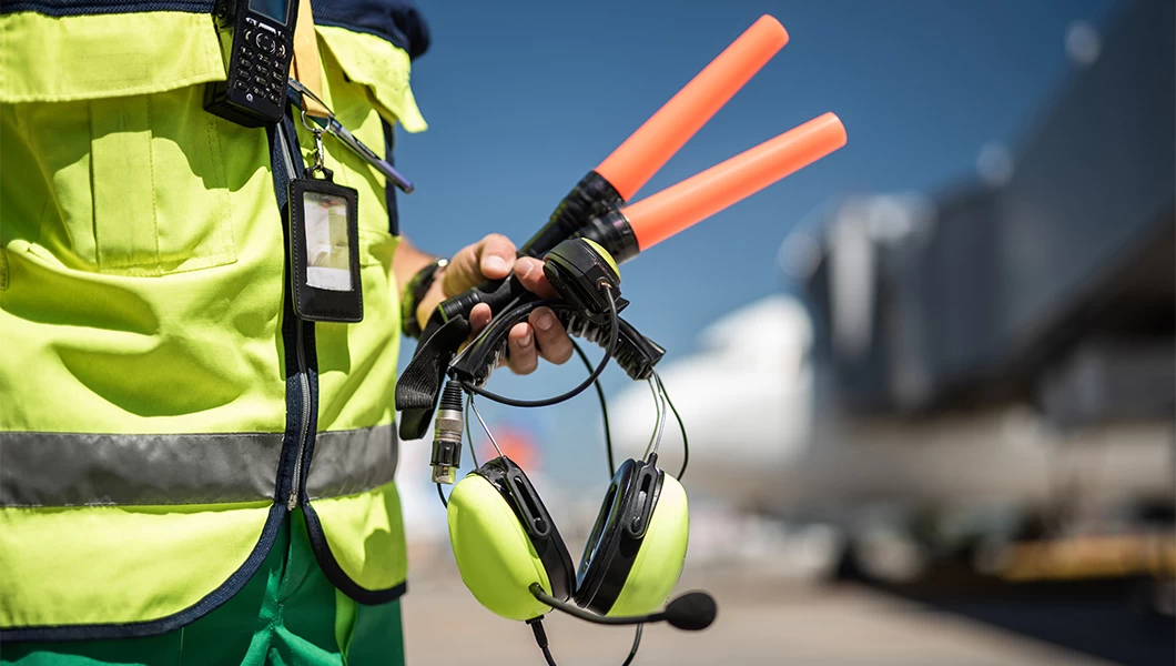 Aircraft marshaller with wands, earmuffs and reflective vest