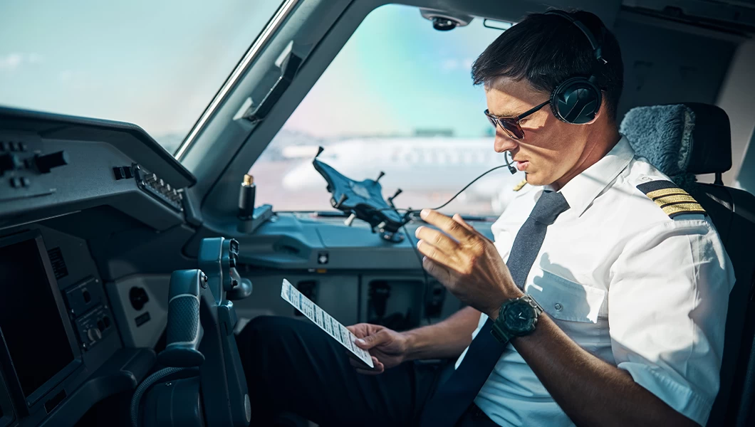 A pilot in the cockpit, communicating with Air Traffic Control