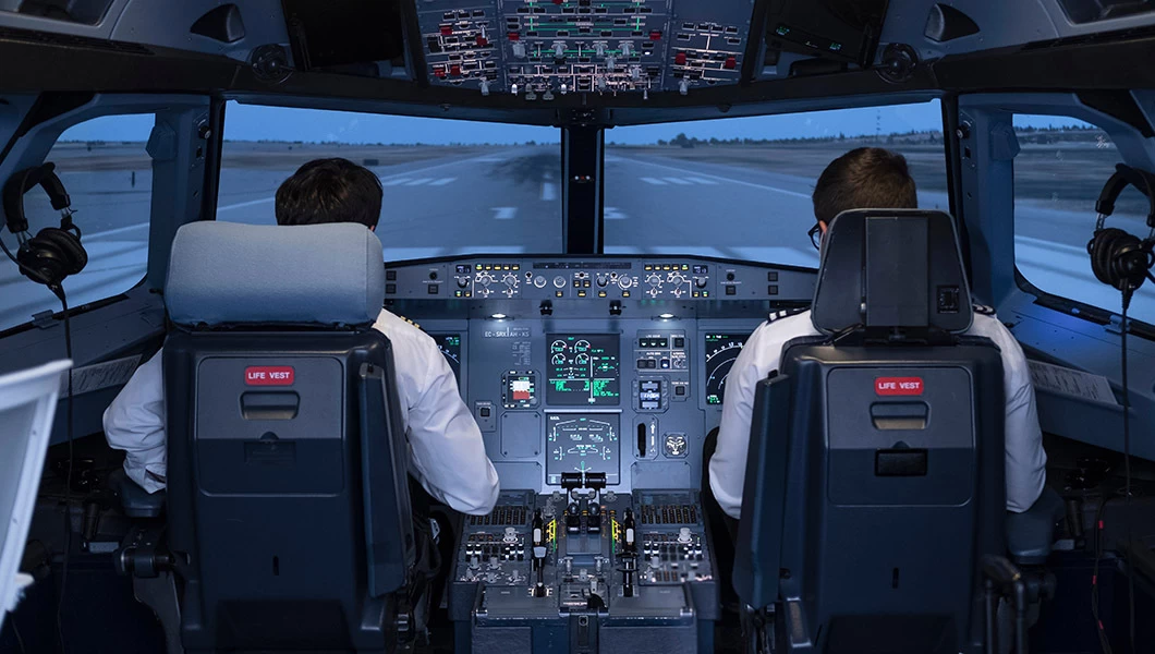 two pilots sitting in a cockpit of a simulator