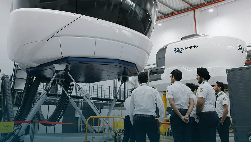 Cadets standing in front of a full flight simulator at BAA Training